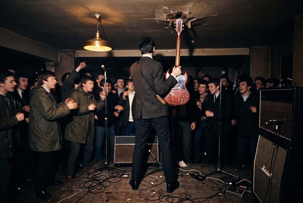 Pete Townshend stands with a damaged guitar beneath the Railway Hotel's low ceiling during a 1964 performance